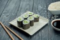 Classic japanese sushi rolls - maki rolls with cucumber on a white, ceramic plate on a black wooden background Royalty Free Stock Photo