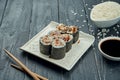 Classic japanese sushi rolls - maki rolls with eel on a white, ceramic plate on a black wooden background