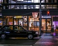 Classic japanese taxi in front of a pedestrian crosswalk and a few shops. Night photography