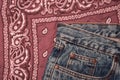 Classic jeans with five pockets close-up. Paisley patterned bandana, classic red and white neckerchief, biker head scarf. Rough