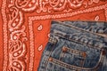 Classic jeans with five pockets close-up. Paisley patterned bandana, classic red and white neckerchief, biker head scarf. Rough