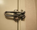 Classic large, sturdy metal latch securing a hotel or motel door to keep out intruders and unwanted guests Royalty Free Stock Photo