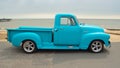 Classic Light Blue Chevrolet 3100 pickup truck on seafront promenade with sea in background