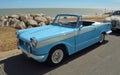 Classic light Blue Triumph Herald open top motor car parked on seafront promenade.