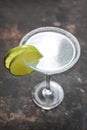 Margarita cocktail in a martini glass with salt rim, decorated with lime, on black stony background, selective focus. Royalty Free Stock Photo