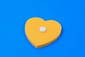 Classic medical white pill with a risk on a heart shaped office sticker. blue background. Selective focus on pill