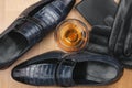 Classic men`s shoes and glass of cognac, gloves and purse on wooden desk. Royalty Free Stock Photo