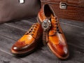 Classic men`s shoes of a light brown shade against the background of men`s leather briefcases