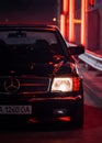 classic Mercedes-Benz W126 on a street with red glowing lights.