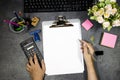 Classic metal clipboard with blank white paper and hand woman calculating monthly expenses, managing budget, entering data in comp