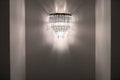 Classic metallic sconce with the lights turned on beautifully illuminates the gray wall. Evening Time. Classic metallic