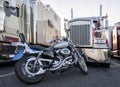 Classic motorcycle as an alternative mode of transport and a hobby of a truck driver while resting is parked near a row of big rig Royalty Free Stock Photo