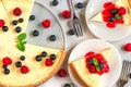 Classic New York cheesecake with two slices of cake in plates with fresh berries, jam and mint on white marble table Royalty Free Stock Photo