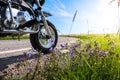 Classic off road motorcycle along a curvy road in the countryside. Wild flowers in the road side at sunset.