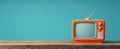 The classic orange television against a vibrant blue backdrop on rustic surface..AI generated image Royalty Free Stock Photo