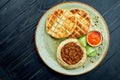 A classic oriental dish - chickpea hummus with olive oil and minced meat served with baked pita in a plate on a dark wood Royalty Free Stock Photo