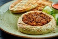 A classic oriental dish - chickpea hummus with olive oil and minced meat served with baked pita in a plate on a dark wood Royalty Free Stock Photo