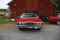 Classic Pairing: Red 1971 Ford LTD with Round Headlights and Red Volvo 142 at a Barn Royalty Free Stock Photo