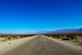 Classic panorama view of an endless straight road running through the barren scenery of the American Southwest with extreme heat Royalty Free Stock Photo