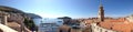 Classic panoramic view of traditional Mediterranean Old Town houses with red tiled roofs, dock and picturesque island background