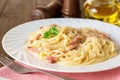 Classic pasta carbonara. Spaghetti with bacon, egg yolk and parmesan cheese on white plate on dark wooden background. Royalty Free Stock Photo