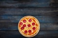 Classic pepperoni pizzai on a wooden stand on a dark wooden background. Top view bottom orientation