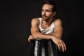 Classic portrait of young handsome bearded sad man in white undershirt and jeans isolated on dark background. Emotions Royalty Free Stock Photo