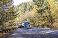 Classic powerful big rig blue semi truck transporting liquid cargo in armored tank semi trailer running on the winding mountain Royalty Free Stock Photo