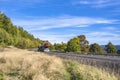 Classic powerful car hauler transporting cars on two level modular semi trailer running on the winding road with dry grass and Royalty Free Stock Photo