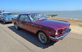 Classic Purple Ford Mustang parked on seafront.