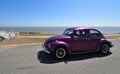 Classic Purple VW Beetle Motor Car being driven along Seafront Promenade.