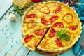 A classic quiche Lorraine pie with buckwheat, mushrooms, paprika, tomatoes, cheese and egg filling on a wooden table.