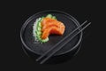 Classic raw salmon sashimi with cucumber on a stylish black ceramic plate on a black background. Japanese traditional food. Photo