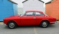 Classic Red Alfa Romeo Motor Car Parked in front of Beach Hut on seafront promenade Royalty Free Stock Photo