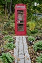 A Classic Red British Phone Booth in Lush Landscaping