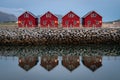Classic red fishing cottages in perfect symmetry sitting along a stone jetty with a slightly blurred reflection. Classic red Royalty Free Stock Photo