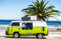 Classic retro camper van parked on a tropical beach on a sunny day