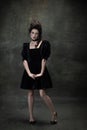 Classic retro portrait of young beautiful woman in image of medieval royal person in black dress isolated on dark