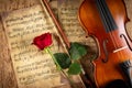 Classic retro violin music string instrumt on old music note sheet paper with red rose flower old oak wood wooden background. Royalty Free Stock Photo