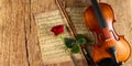 Classic retro violin music string instrumt on old music note sheet paper with red rose flower old oak wood wooden panorama copy Royalty Free Stock Photo