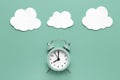 Classic round alarm clock and white clouds on the mint green background. Royalty Free Stock Photo