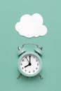 Classic round alarm clock and white clouds on the mint green background. Royalty Free Stock Photo