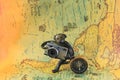 Classic round compass and souvenir figurine with camera on background of old vintage map of world