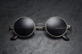 Round gray metal sunglasses on on black slate background