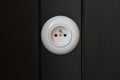 A classic round white electrical socket is mounted on vertical black wooden paneling Royalty Free Stock Photo