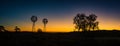 Farm windmills silhouetted against the rising sun