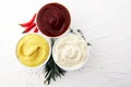 Classic set of sauces in white saucers: American yellow mustard, ketchup, mayonnaise. Royalty Free Stock Photo