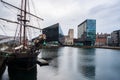 A classic ship set against the Liverpool cityscape at the Liverpool Docks, Port of Liverpool, late on a cloudy afternoon