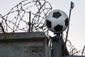 A classic soccer ball against a background of concrete fence, barbed wire and barbed tape. Closed Russian Football Club Royalty Free Stock Photo