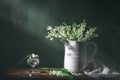 Classic still life with beautiful white Lily of the valley bouquet in white jar and a glass of water in ray of light. Art